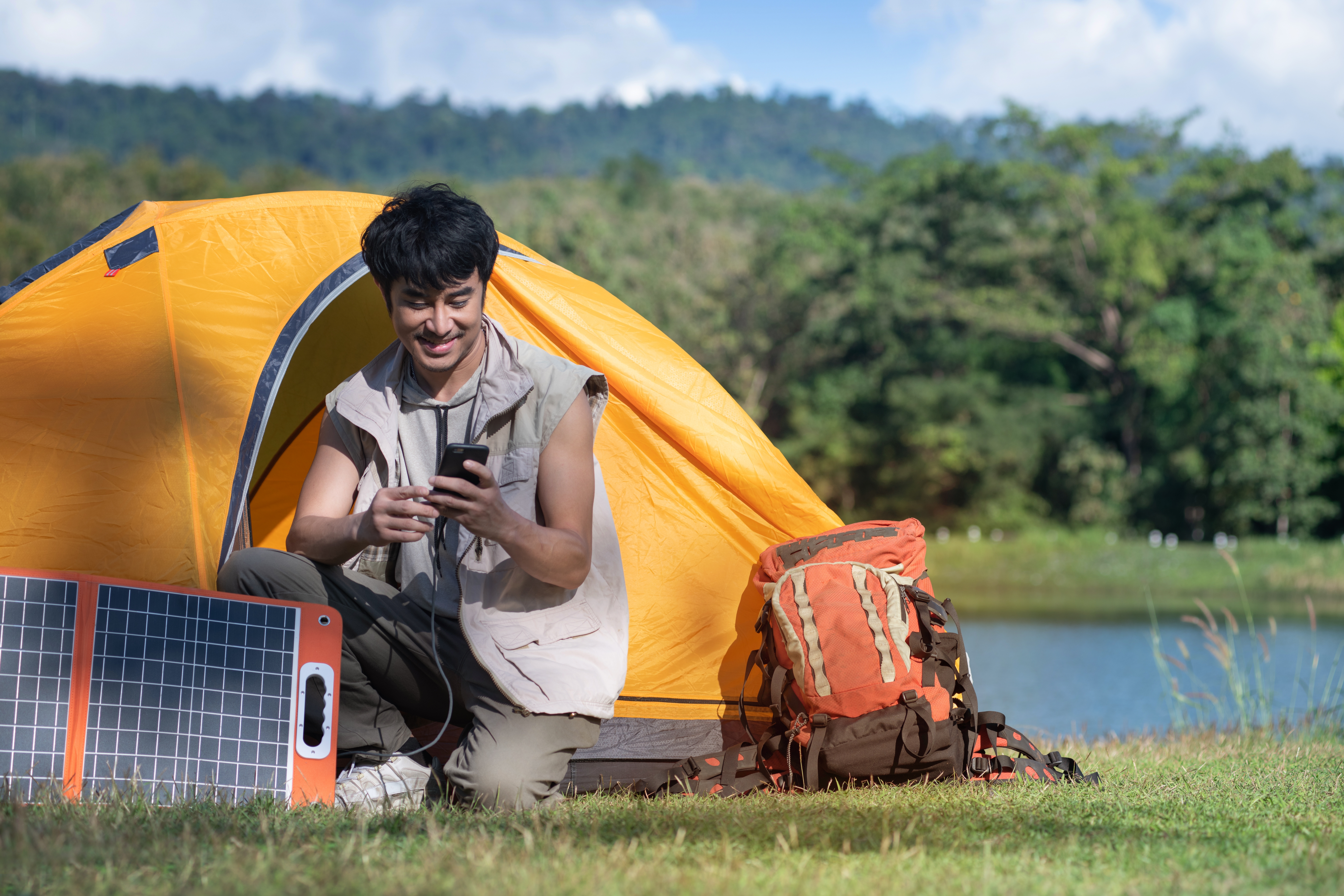 Man op camping laadt telefoon op met zonnepanelen
