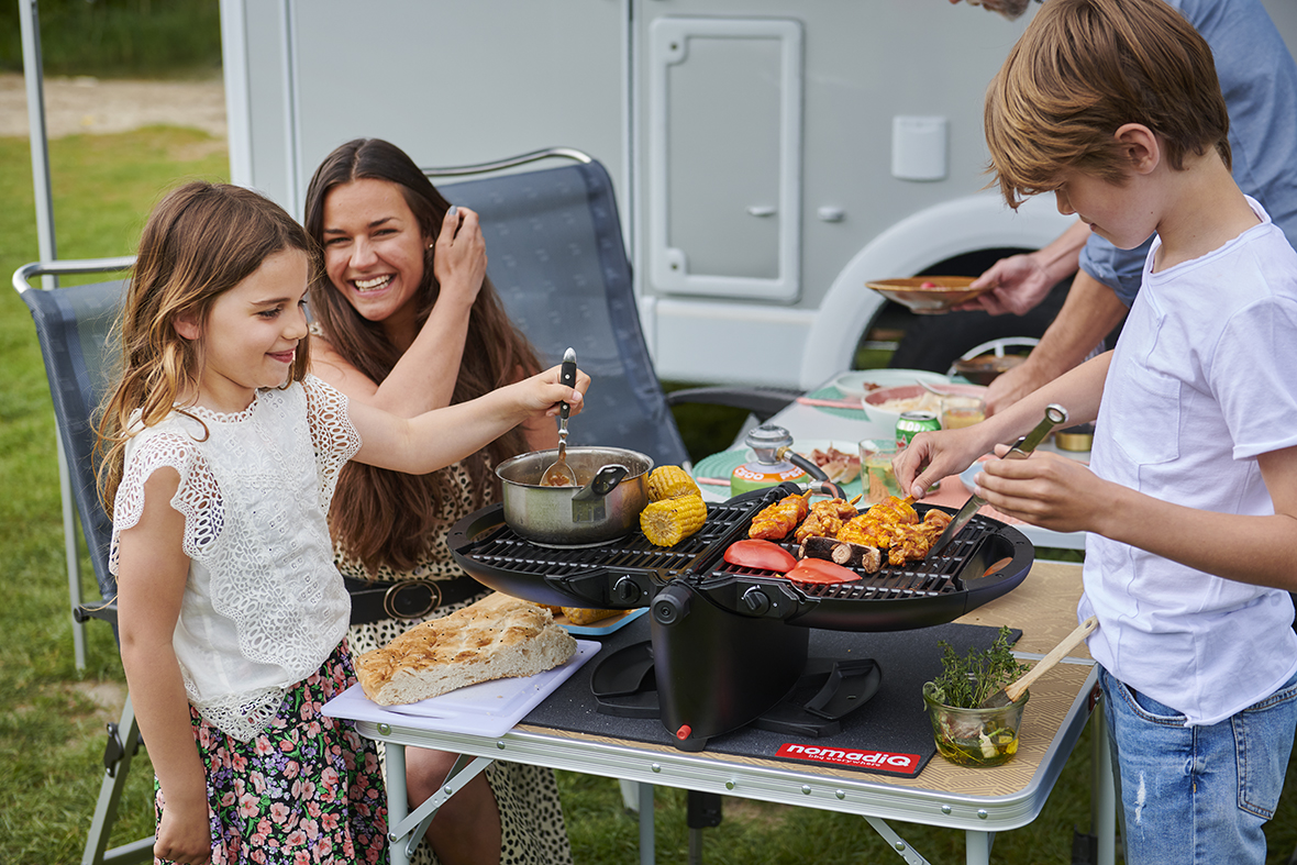 Gezin op camping maakt eten klaar op NomadiQ BBQ