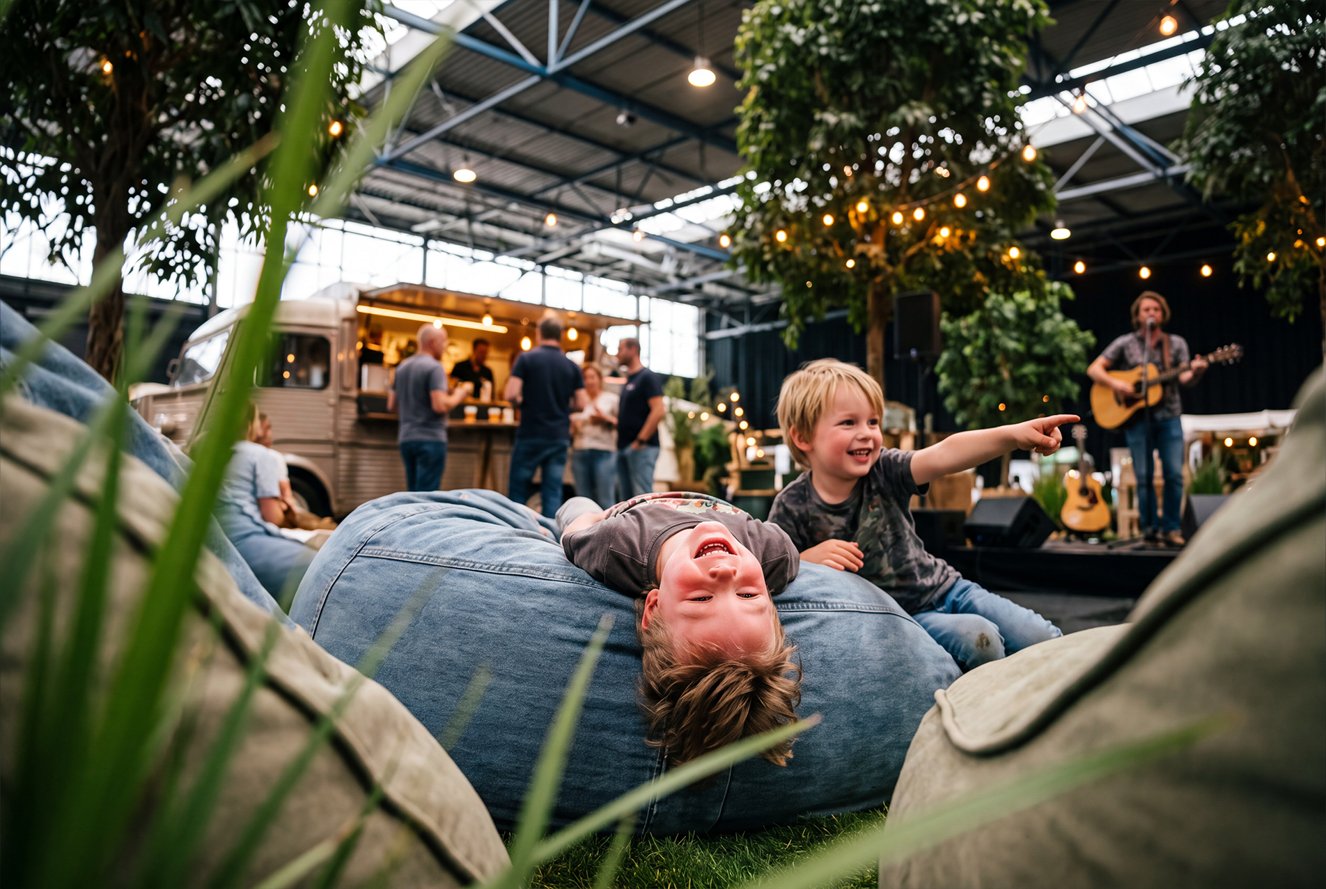 Kinderen spelen op zitzakken terwijl een muzikant optreedt in Het Utrechtse Kampeerdorp.