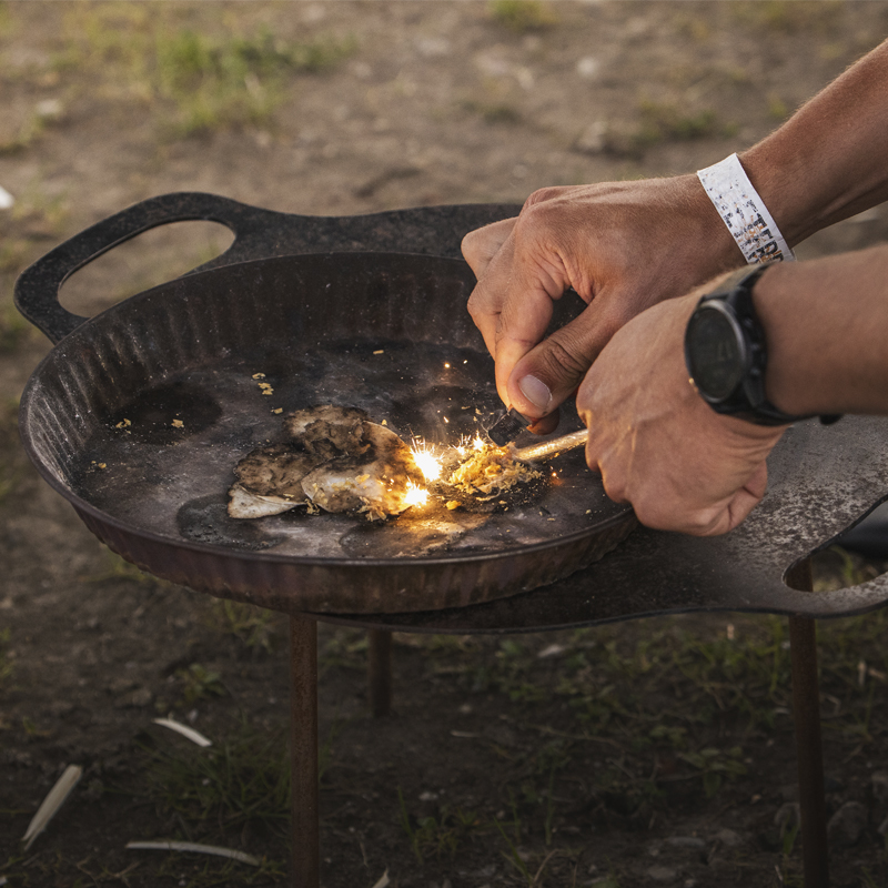 A participant starts a fire with a fire steel during WilderWonder’s “Fire &amp; Knife” workshop