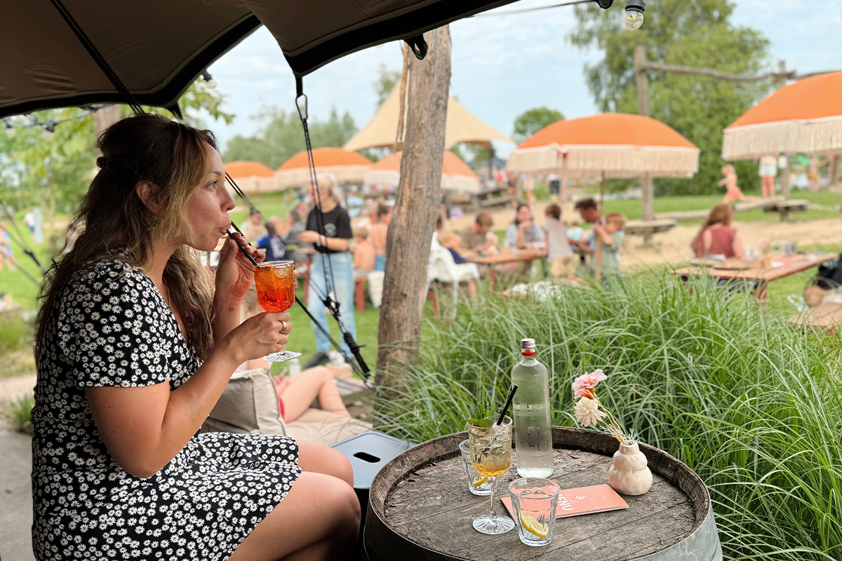 Bezoeker geniet van een drankje op het terras van Buitengoed de Boomgaard
