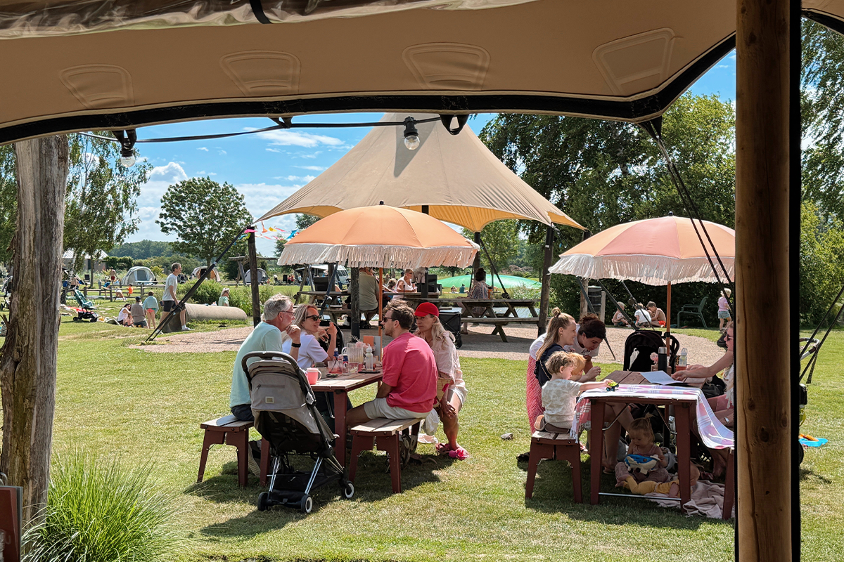 Gezinnen genieten aan picknicktafels op het terras van Buitengoed de Boomgaard