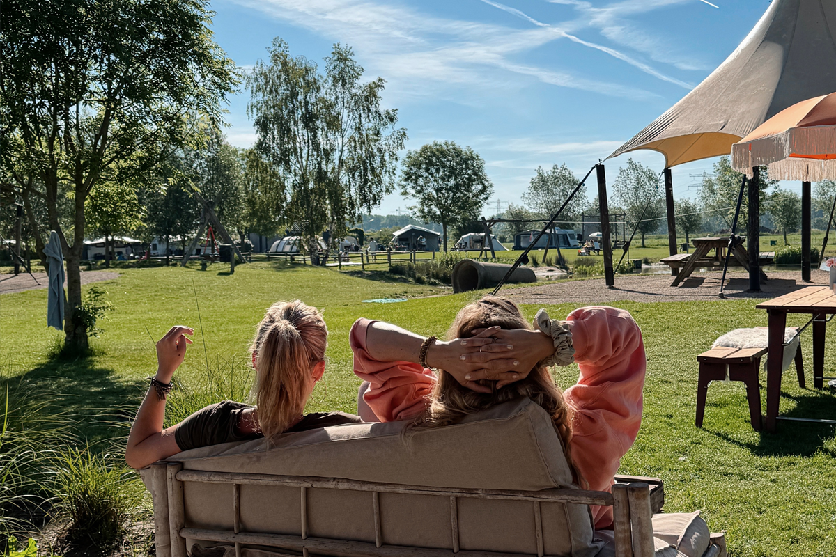 Twee bezoekers ontspannen op het terras met uitzicht over Buitengoed de Boomgaard