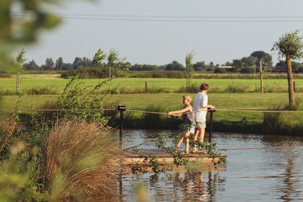 Kinderen varen met een trek-vlot over het water bij Buitengoed de Boomgaard
