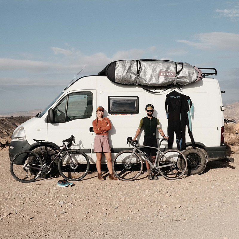 campervan op strand met 2 mensen ervoor en fietsen