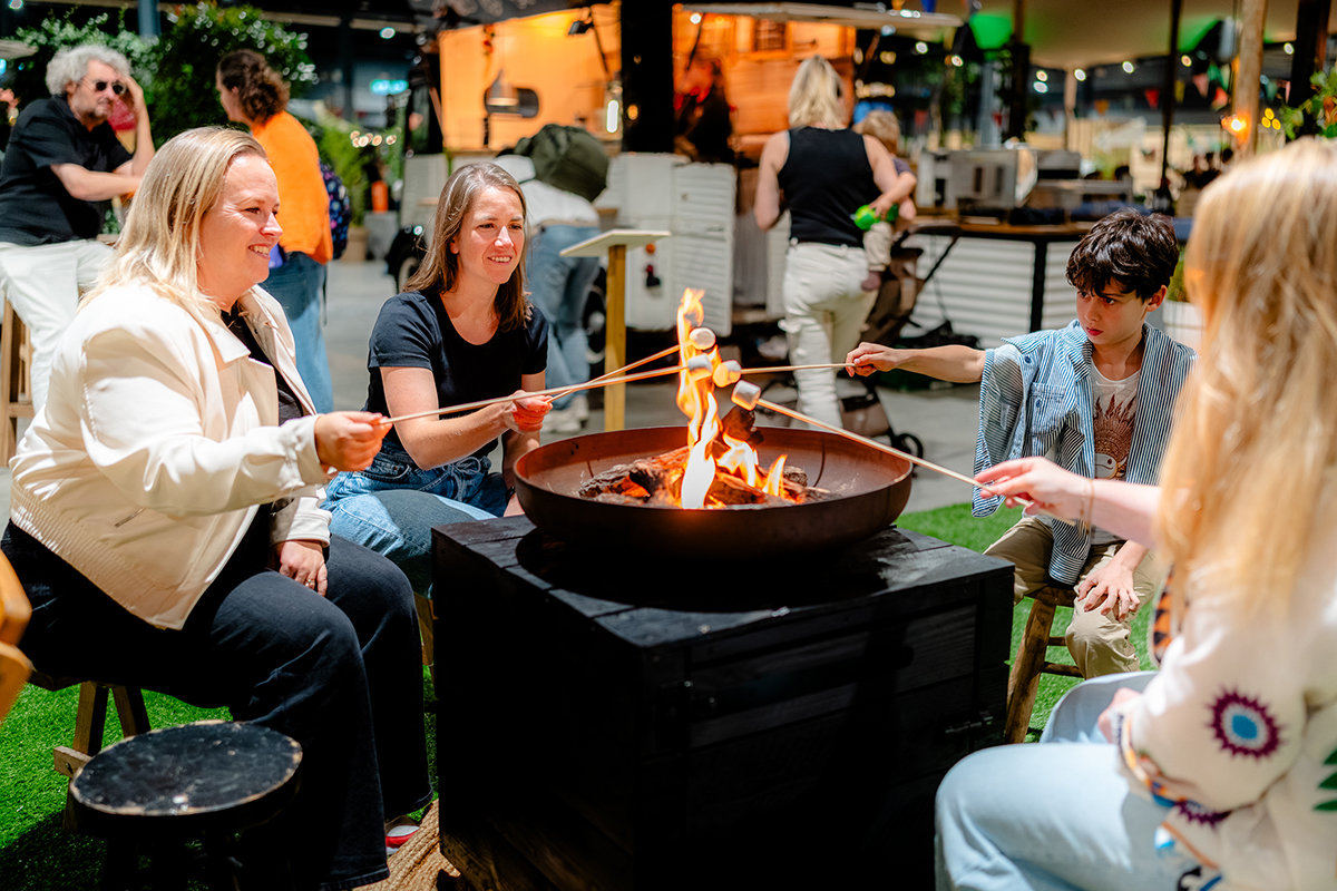 3 volwassenen en kind die marshmallows roosteren boven vuur